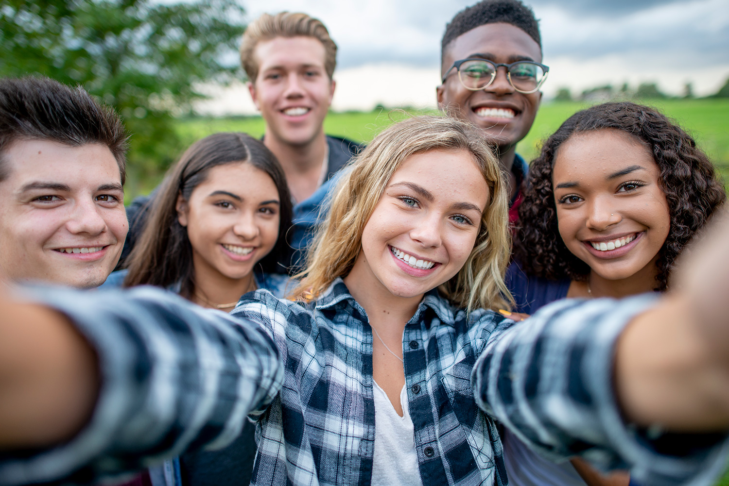 A group of multi-ethnic students taking a selfie outside. They are dressed casually and having fun together in a group.